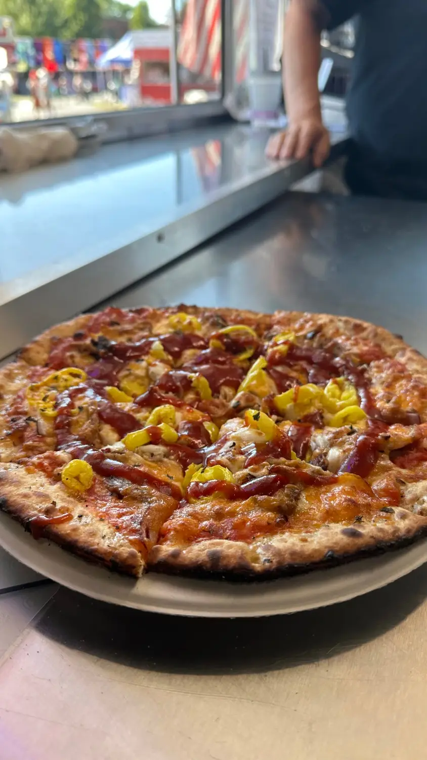 A barbecue chicken and banana pepper pizza on the counter of the trailer at a festival
